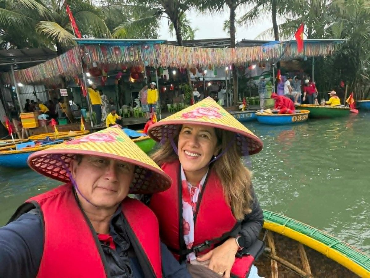 Apple and family in conical hats on a Hoi An basket boat