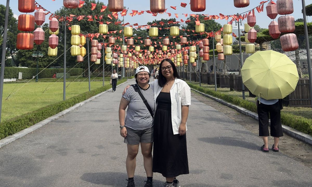 Two friends beneath a lantern-lined walkway in Hanoi