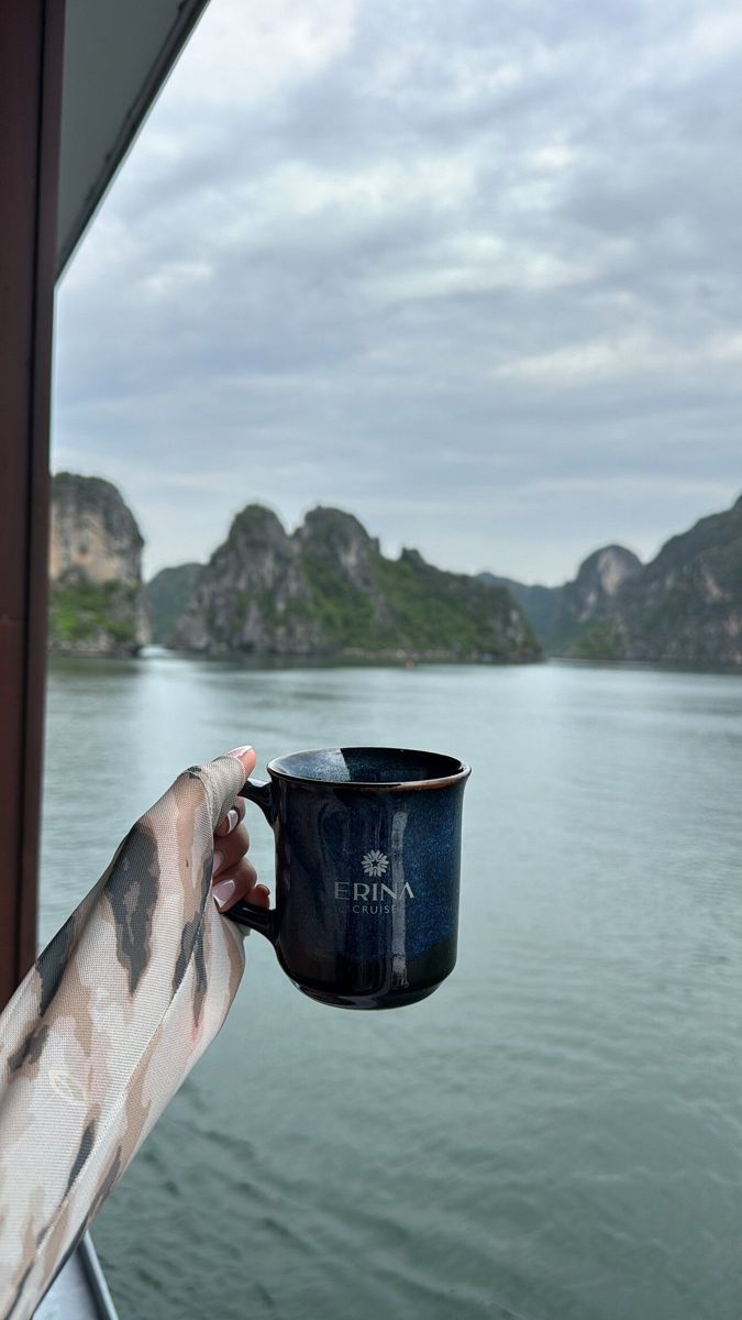 An Erina Cruise mug held up against the Ha Long Bay karst